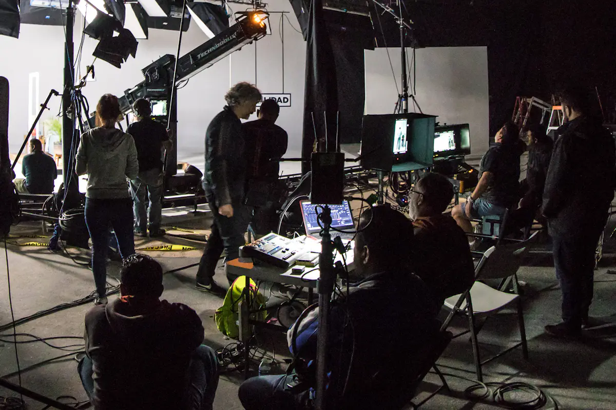A film crew at work on a darkened soundstage, gathered around monitors